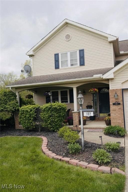 view of front of house featuring a front lawn, a porch, and brick siding