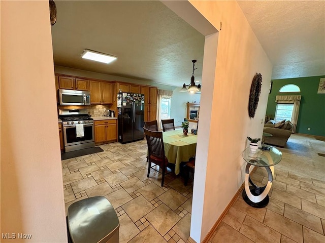 kitchen featuring brown cabinetry, stainless steel appliances, light countertops, and a healthy amount of sunlight