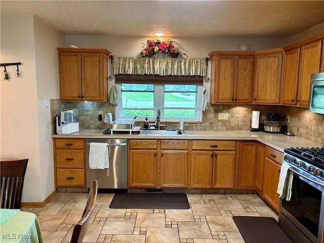 kitchen featuring a sink, stainless steel appliances, tasteful backsplash, and light countertops