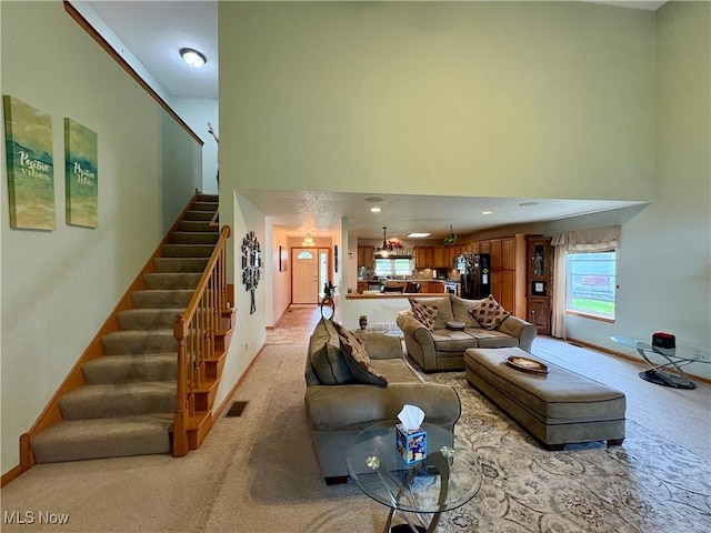 living room featuring baseboards, a high ceiling, light colored carpet, and stairway