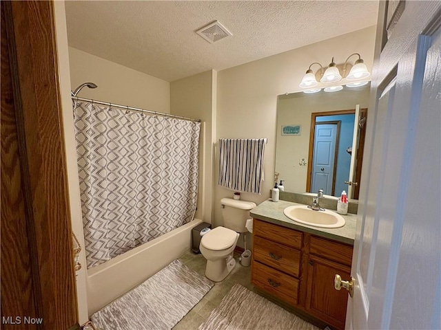 bathroom with toilet, vanity, a textured ceiling, visible vents, and tile patterned floors
