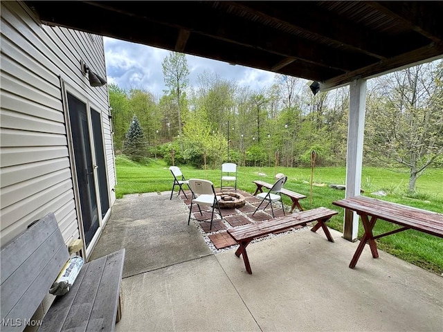 view of patio / terrace with an outdoor fire pit and a view of trees