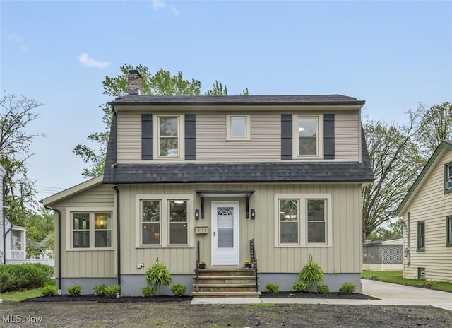 view of front of property featuring entry steps, a shingled roof, and a chimney