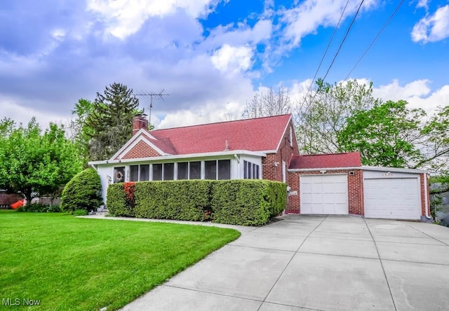 view of front of house with brick siding, driveway, a garage, a front yard, and a chimney