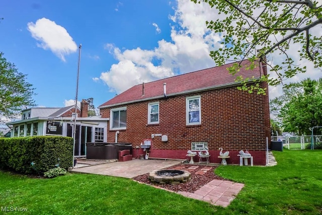 back of house featuring a hot tub, a patio area, fence, brick siding, and a lawn