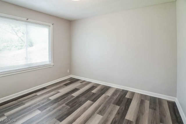 unfurnished room featuring a wealth of natural light, baseboards, and wood finished floors