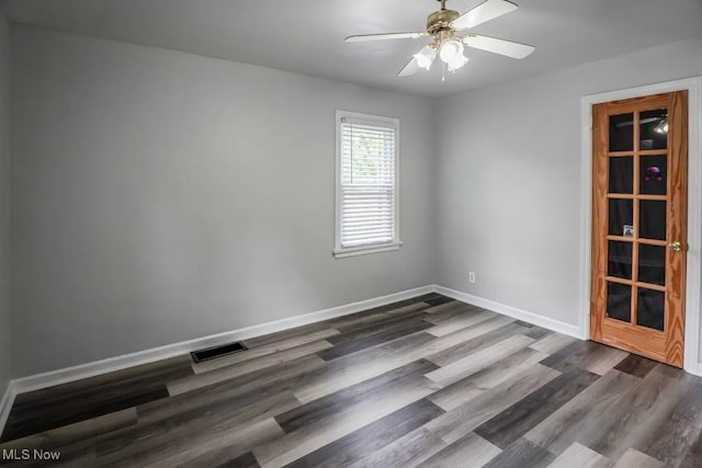 spare room with baseboards, dark wood-style flooring, visible vents, and a ceiling fan