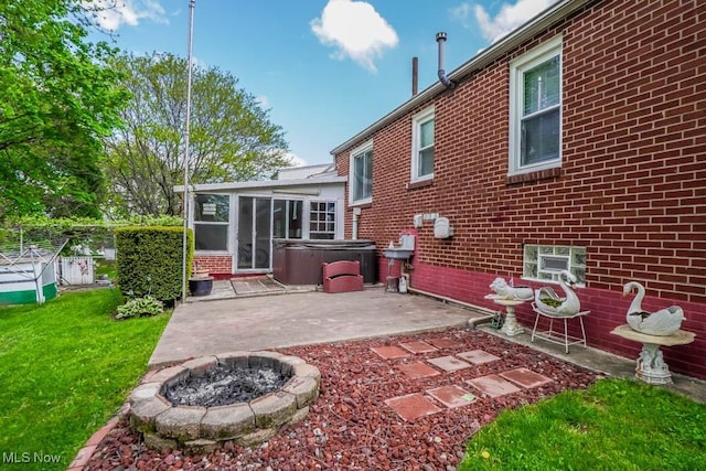 back of house featuring a patio, a sunroom, a yard, a hot tub, and brick siding