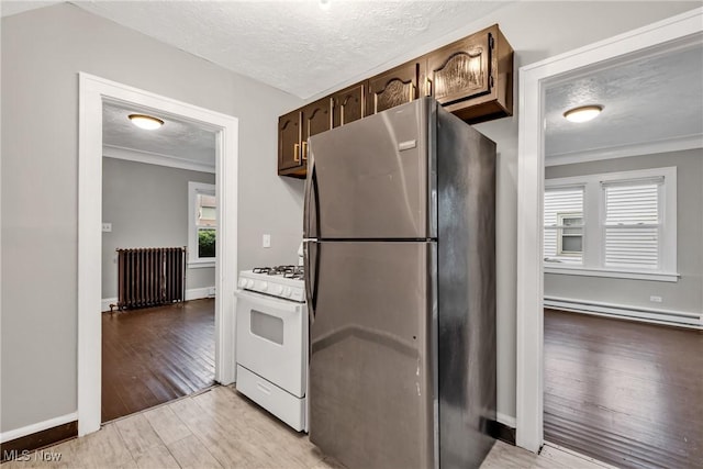 kitchen with freestanding refrigerator, a baseboard radiator, a textured ceiling, radiator heating unit, and white gas range oven