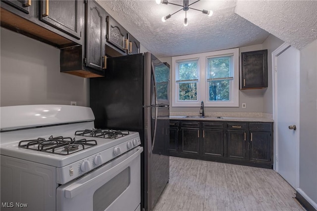 kitchen featuring a textured ceiling, a sink, light wood-style floors, light countertops, and gas range gas stove
