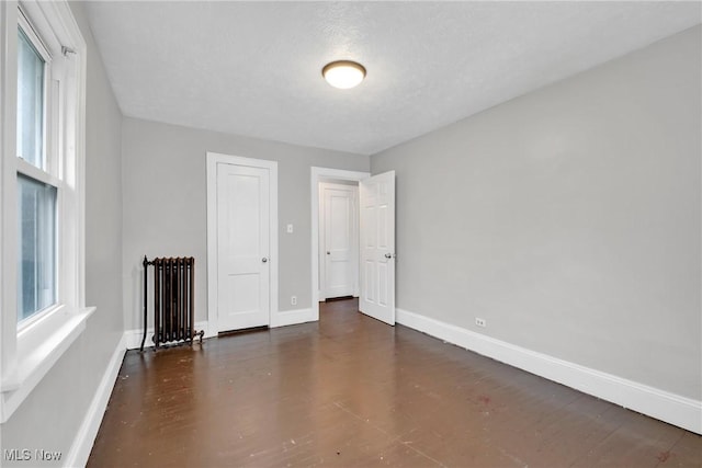 interior space with radiator, wood finished floors, and baseboards