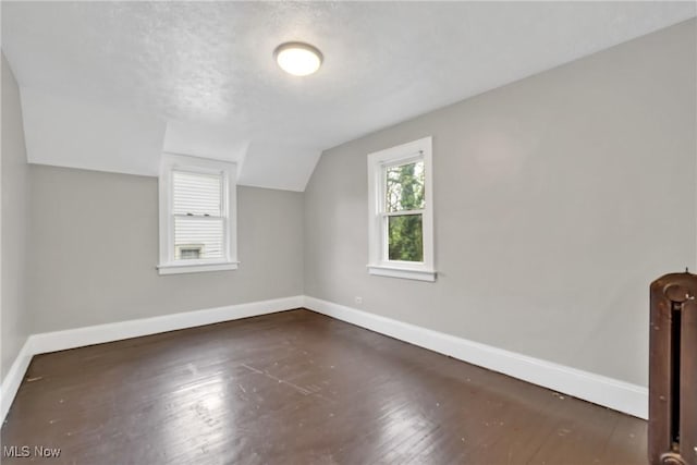 additional living space with vaulted ceiling, hardwood / wood-style flooring, and baseboards