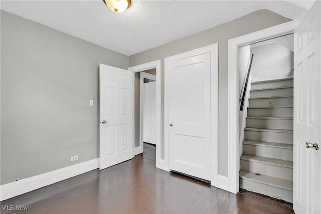 unfurnished bedroom featuring a closet, wood finished floors, baseboards, and a textured ceiling