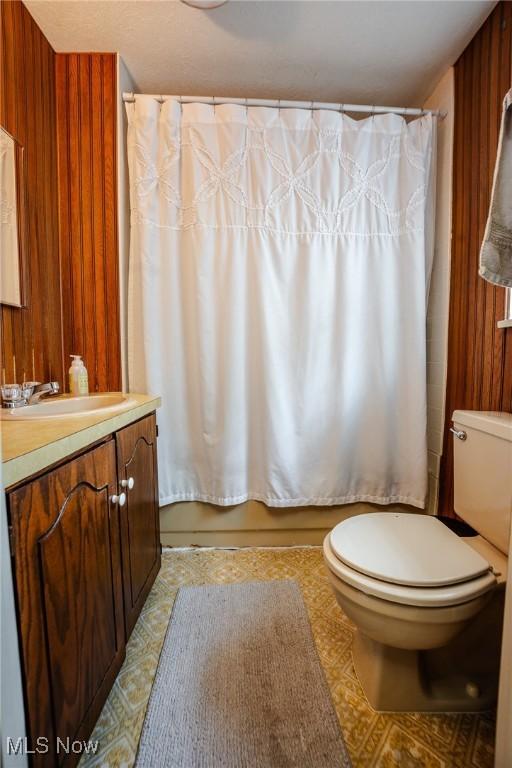 4991 Walnut St, Sugarcreek, OH 44681 - bathroom with toilet, wooden walls, vanity, and shower / bathtub combination with curtain