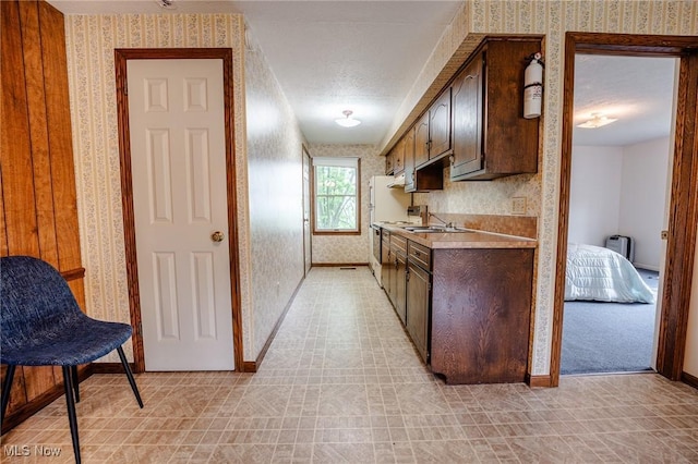 4991 Walnut St, Sugarcreek, OH 44681 - kitchen with baseboards, light countertops, wallpapered walls, and dark brown cabinetry