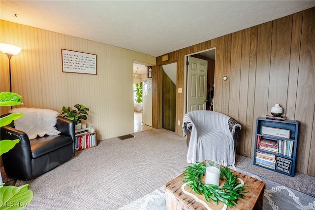4991 Walnut St, Sugarcreek, OH 44681 - living area featuring wooden walls, carpet, and visible vents