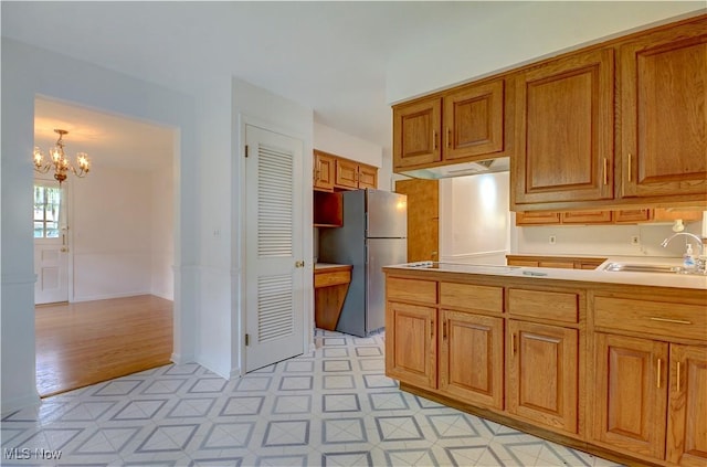 4840 W 228th St, Fairview Park, OH 44126 - kitchen featuring a sink, freestanding refrigerator, a chandelier, brown cabinets, and light flooring