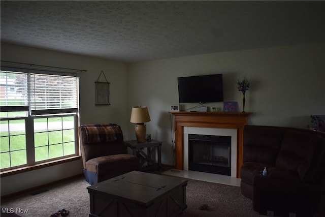carpeted living room featuring a textured ceiling and a fireplace with flush hearth