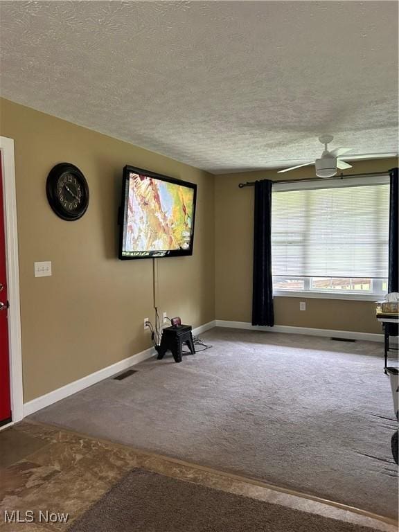 interior space featuring a textured ceiling, baseboards, a ceiling fan, and carpet