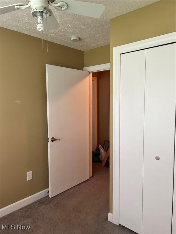 unfurnished bedroom featuring a closet, a textured ceiling, carpet floors, a ceiling fan, and baseboards