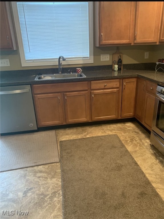 kitchen with dishwasher, dark countertops, stove, and a sink