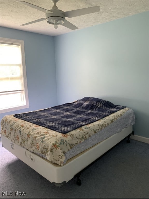 bedroom featuring a textured ceiling, baseboards, ceiling fan, and carpet floors