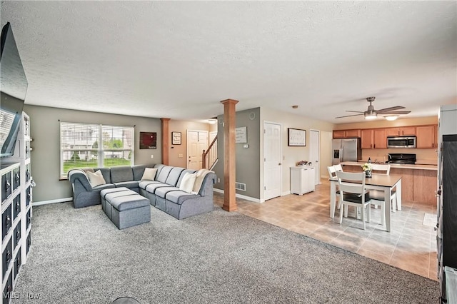 living room with a ceiling fan, a textured ceiling, stairway, baseboards, and light carpet