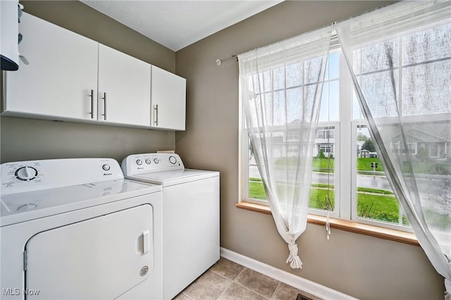 laundry room with cabinet space, washing machine and dryer, light tile patterned floors, and baseboards
