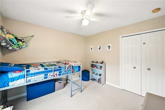 carpeted bedroom with baseboards, a textured ceiling, a closet, and a ceiling fan