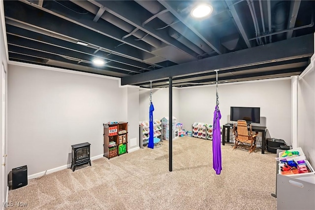 finished basement with a wood stove, carpet flooring, and baseboards