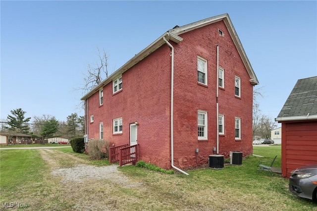 2419 Carpenter Rd, Ashtabula, OH 44004 - view of home's exterior with central AC, brick siding, and a lawn