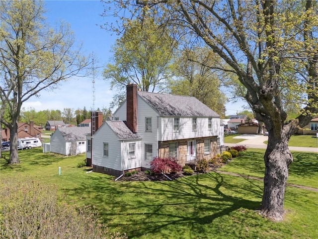 view of property exterior featuring a chimney, a shingled roof, and a lawn