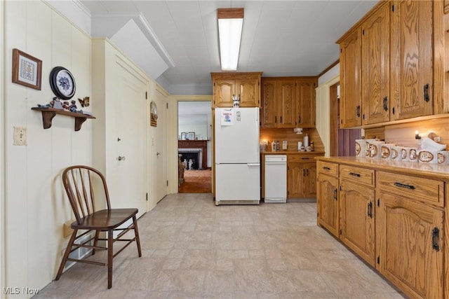 kitchen featuring freestanding refrigerator, light countertops, brown cabinetry, and stone finish flooring
