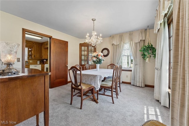 dining area featuring baseboards, a notable chandelier, and light colored carpet