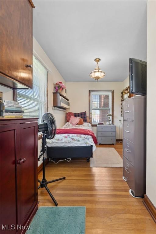 bedroom with light wood finished floors and a wall unit AC
