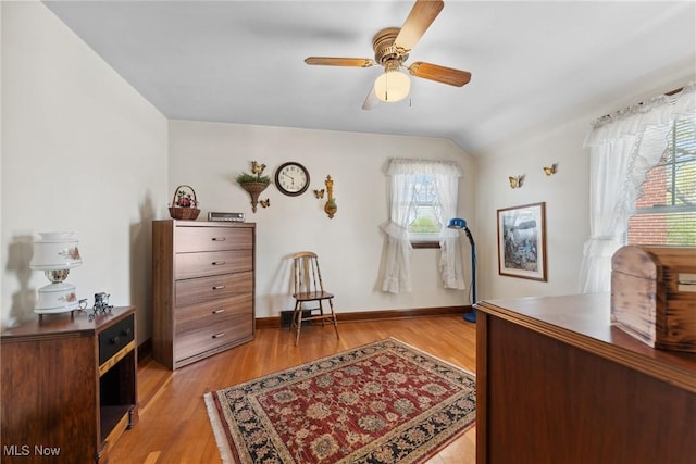 bedroom featuring baseboards, multiple windows, light wood-style floors, and vaulted ceiling