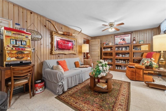 living area featuring light floors, wooden walls, and a ceiling fan