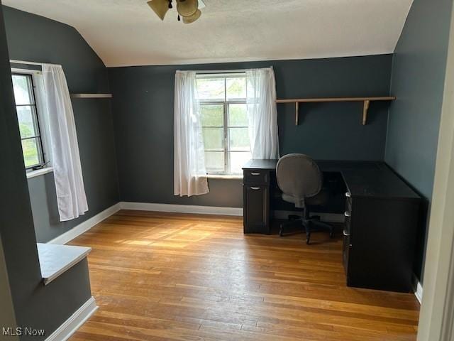 office space featuring lofted ceiling, baseboards, a ceiling fan, and light wood-style floors