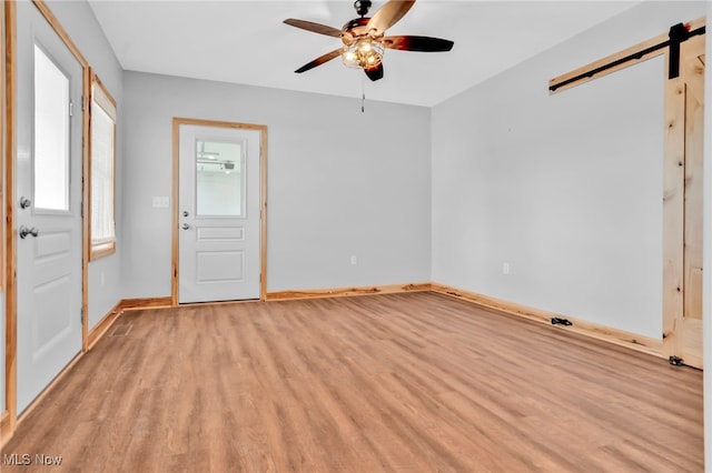 1250 Alamo Rd SE, Carrollton, OH 44615 - empty room with light wood-type flooring, a barn door, baseboards, and ceiling fan