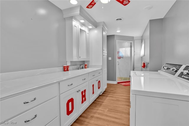 1250 Alamo Rd SE, Carrollton, OH 44615 - laundry area with light wood-style flooring, a sink, washing machine and clothes dryer, visible vents, and ceiling fan