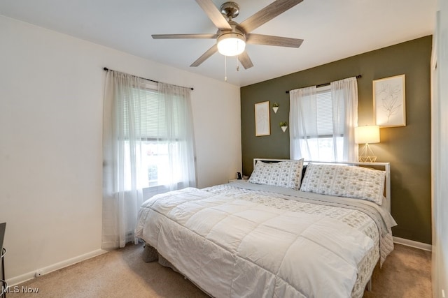 bedroom featuring carpet flooring, multiple windows, baseboards, and a ceiling fan