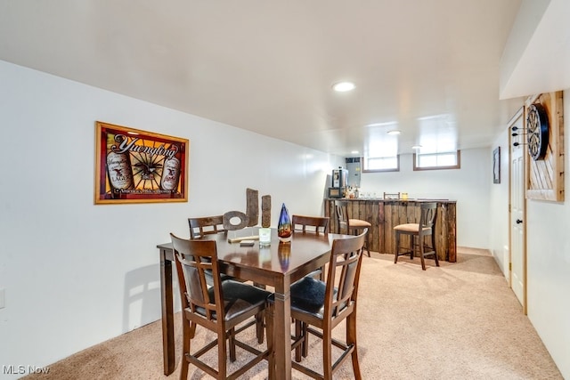 dining room with light colored carpet, bar, and recessed lighting