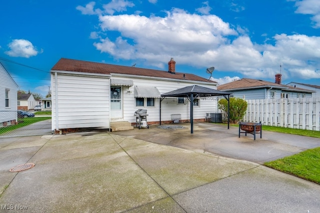 back of property featuring a chimney, fence, a patio, central AC unit, and a gazebo