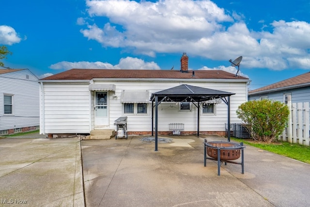 rear view of house with a chimney, fence, a patio, a gazebo, and a fire pit