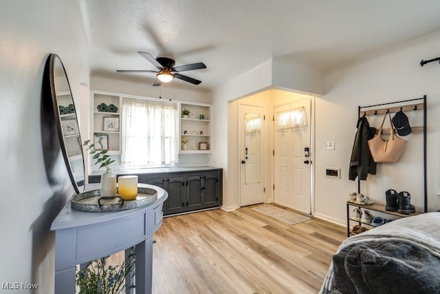 entryway with light wood finished floors, baseboards, and a ceiling fan