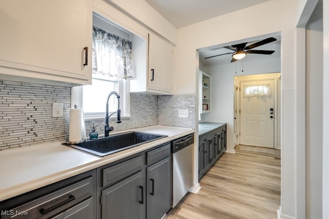 kitchen featuring a sink, stainless steel dishwasher, ceiling fan, light wood-style floors, and decorative backsplash