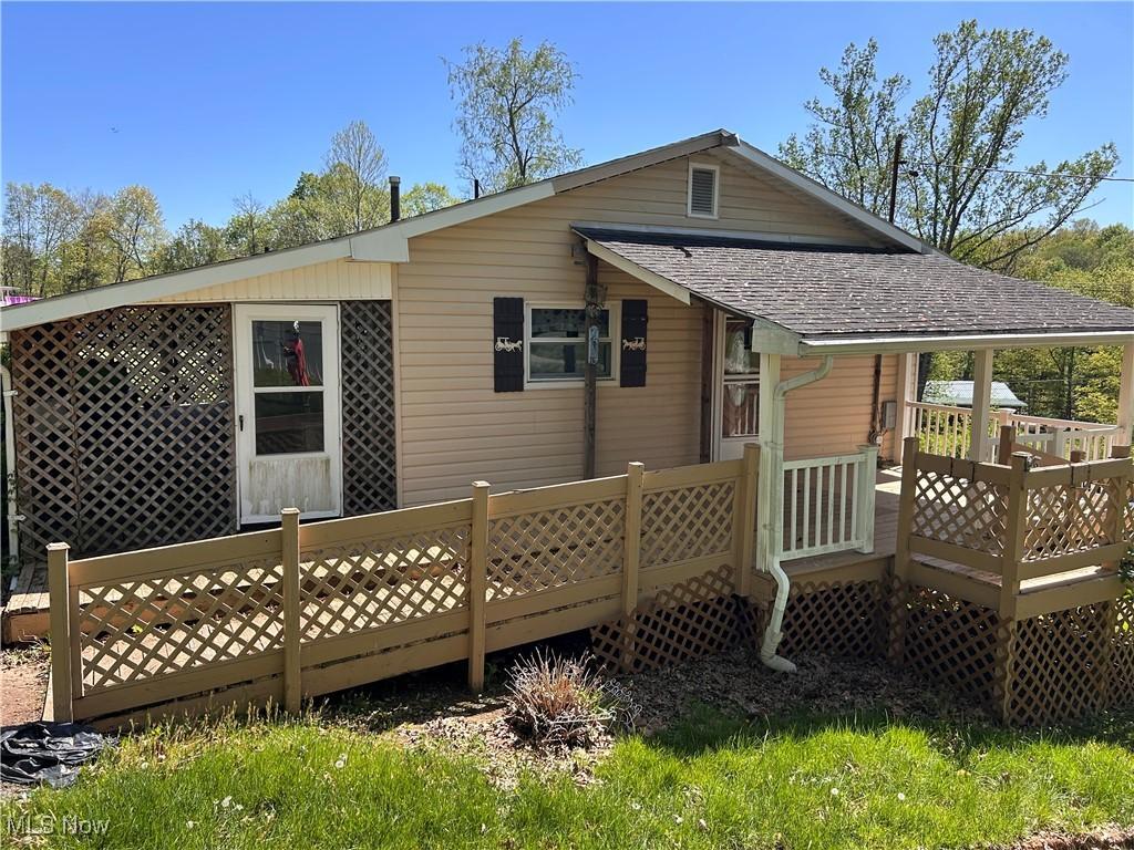 back of house with a shingled roof and a deck