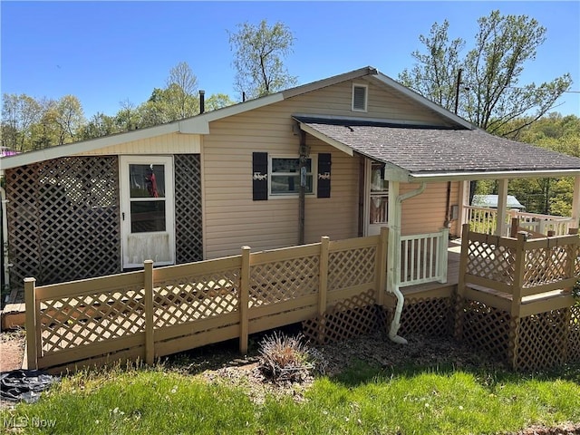 back of house with a shingled roof and a deck