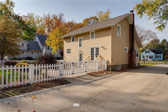 rear view of property with a fenced front yard and a chimney