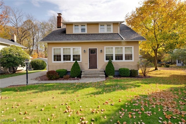 bungalow-style house featuring a chimney, a front yard, and roof with shingles